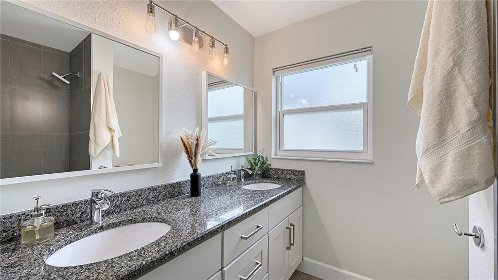 2115 Grove Street Sarasota, FL 34239 - Photo 25 of 40 a bathroom with a granite countertop sink a mirror and a window