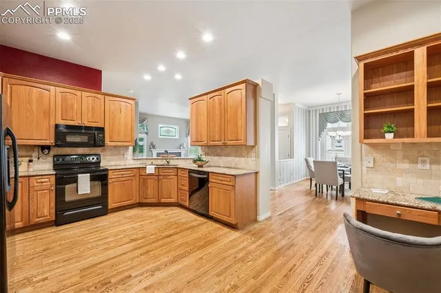 a large kitchen with kitchen island granite countertop a stove a sink a refrigerator and wooden cabinets