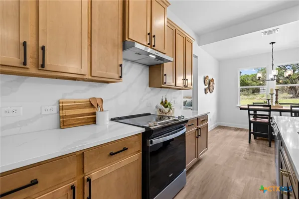 a kitchen with stainless steel appliances granite countertop a stove a sink and a microwave