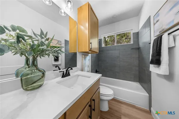 a bathroom with a granite countertop sink a toilet and bathtub
