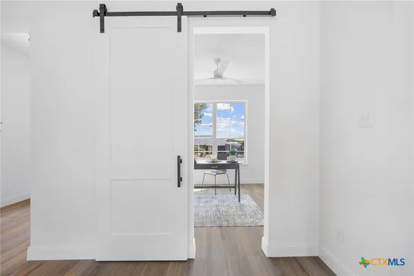 a view of a hallway with wooden floor and a bathroom