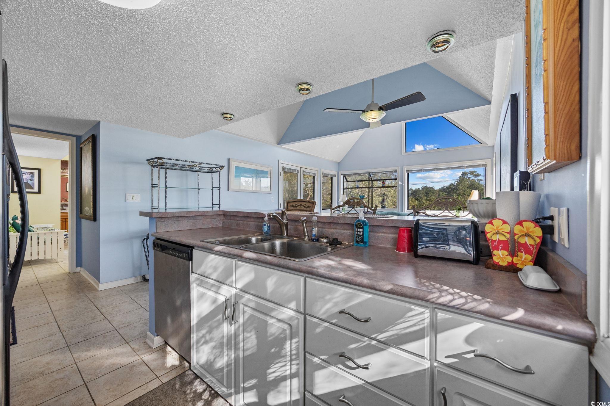 351 Lake Arrowhead Road, Unit 1301 Myrtle Beach, SC 29572 - Photo 14 of 40 Kitchen featuring dark countertops, light tile patterned flooring, a textured ceiling, vaulted ceiling, and dishwasher