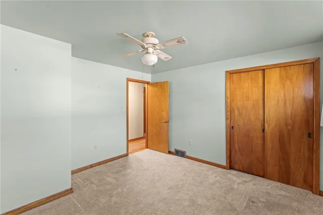 a view of an empty room and chandelier fan