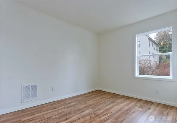 a view of an empty room with wooden floor and a window