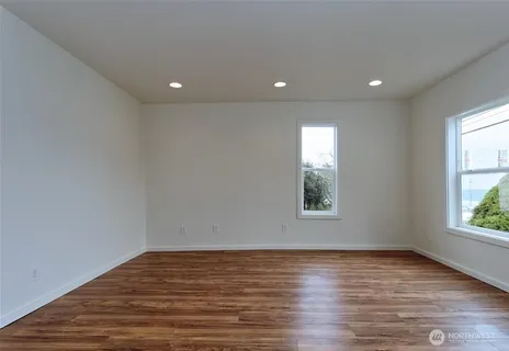 an empty room with wooden floor and windows