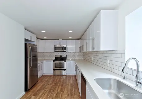 a kitchen with stainless steel appliances a sink dishwasher a refrigerator cabinets and wooden floor