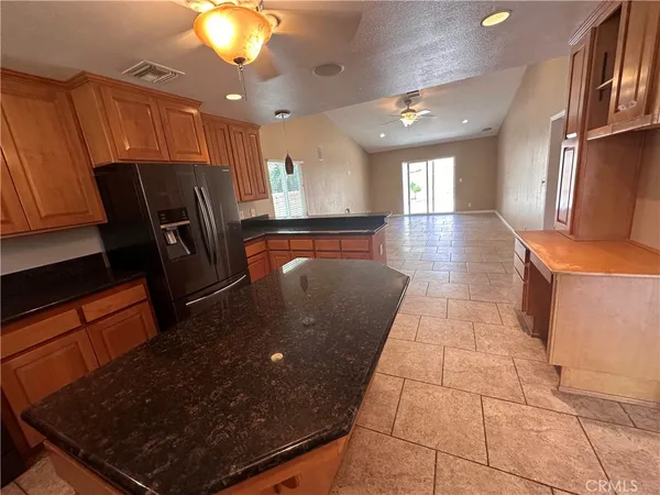 a kitchen with stainless steel appliances granite countertop a refrigerator a stove top oven and a sink with granite countertops