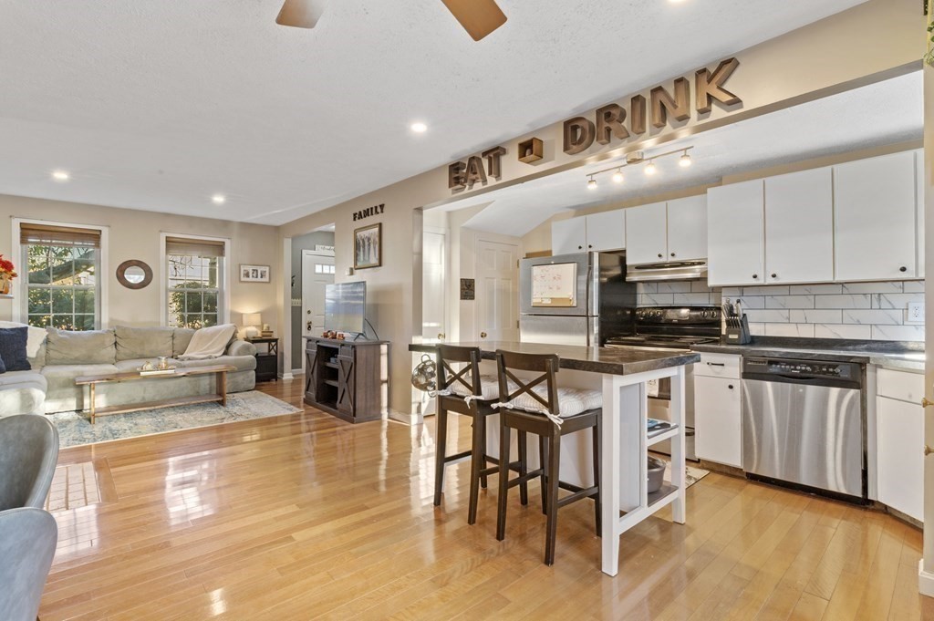 9 Sudbury Street, Unit 9 Maynard, MA 01754 - Photo 5 of 35 a kitchen with stainless steel appliances kitchen island granite countertop a stove a sink a dining table and chairs with wooden floor
