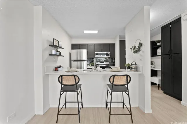 a kitchen with stainless steel appliances granite countertop a dining table chairs cabinets and a refrigerator