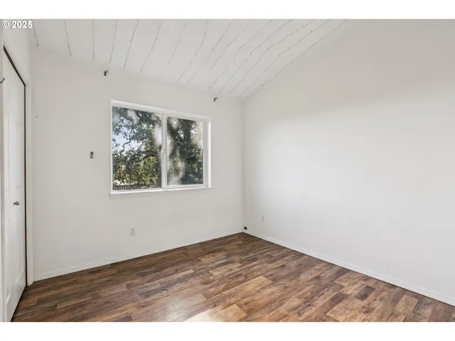 a view of an empty room with window and closet
