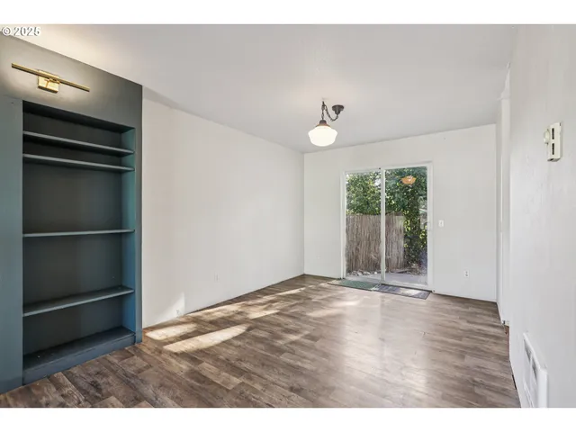 a view of an empty room with a window and wooden floor