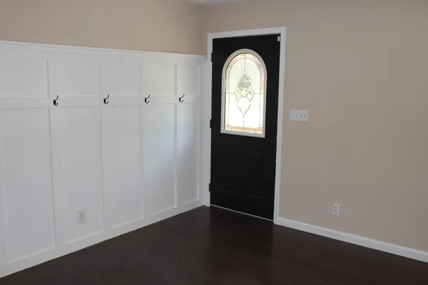 an empty room with wooden floor closet and windows