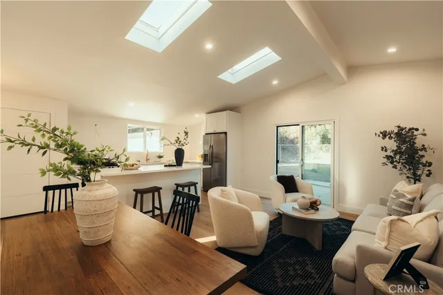a living room with furniture a potted plant and open kitchen view