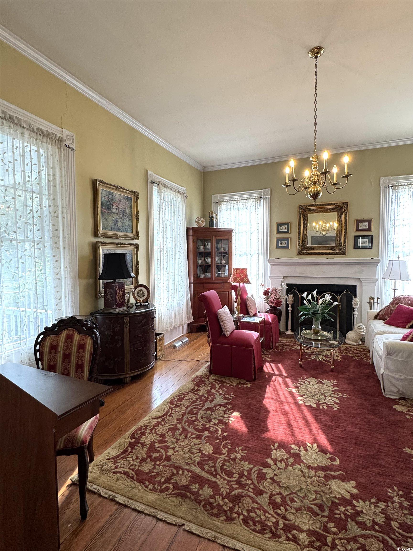 10463 County Line Road Hemingway, SC 29554 - Photo 6 of 40 Living area featuring a fireplace, hardwood / wood-style floors, ornamental molding, and a chandelier