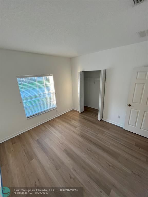 9704 Windrift Circle Fort Pierce, FL 34945 - Photo 16 of 21 an empty room with wooden floor and windows