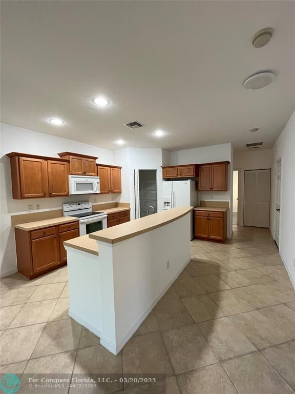 9704 Windrift Circle Fort Pierce, FL 34945 - Photo 6 of 21 a large kitchen with stainless steel appliances a large counter top and a stove top oven