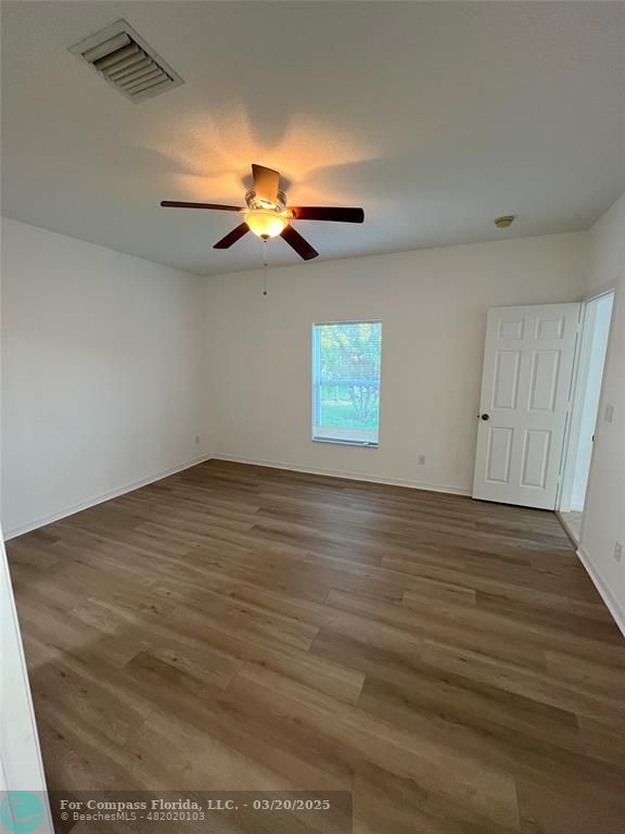 9704 Windrift Circle Fort Pierce, FL 34945 - Photo 9 of 21 an empty room with wooden floor fan and windows