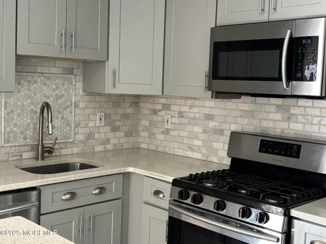 a kitchen with granite countertop white cabinets stainless steel appliances and sink