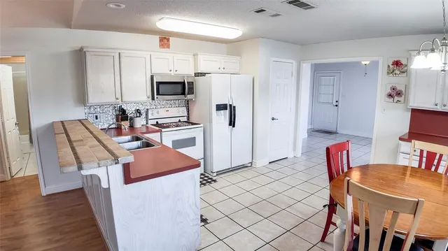 a kitchen with stainless steel appliances kitchen island granite countertop a refrigerator a stove a sink dishwasher and a dining table with wooden floor