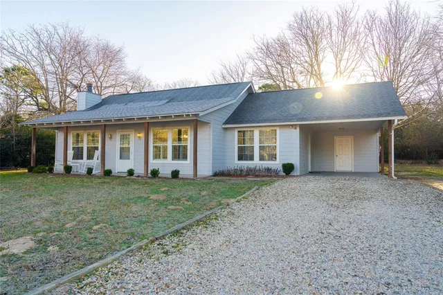 a view of a house with a yard and large tree