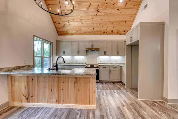 a kitchen with a sink a stove cabinets and wooden floor