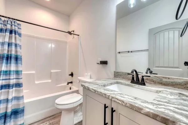 a bathroom with a granite countertop sink toilet and shower