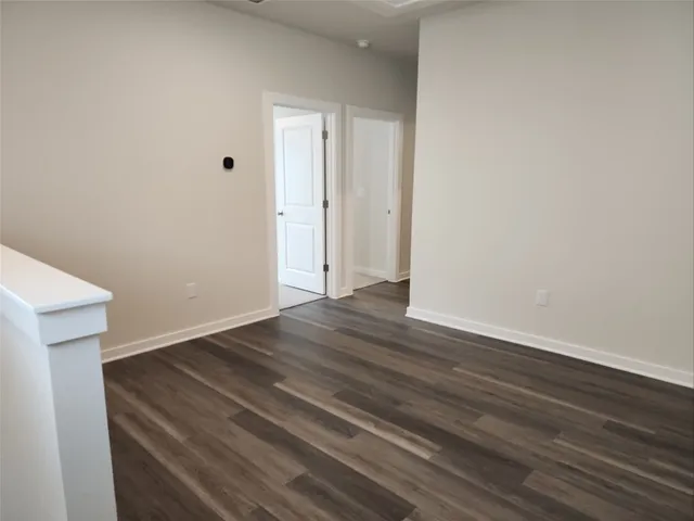 a view of an empty room with wooden floor and window