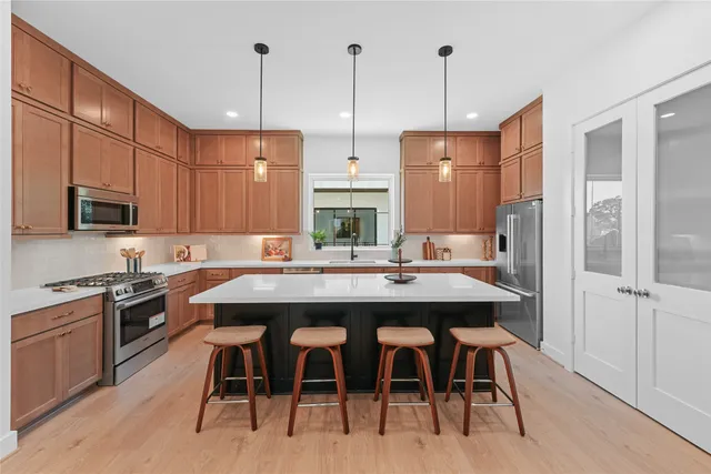 a kitchen with stainless steel appliances kitchen island granite countertop a sink a stove and chairs