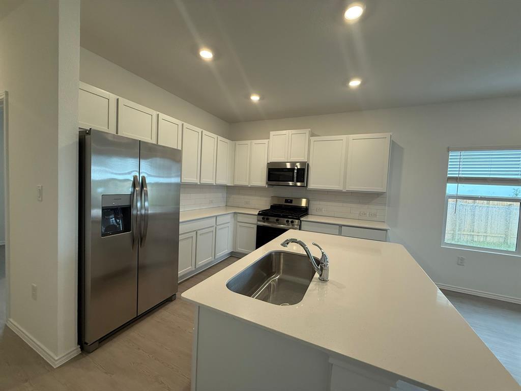 106 Brabham Loop Hutto, TX 78634 - Photo 11 of 40 Kitchen featuring light cabinetry, stainless steel appliances, a subway tile backsplash, and a central island with an undermount sink and light-toned countertop