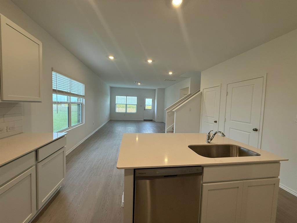 106 Brabham Loop Hutto, TX 78634 - Photo 16 of 40 Open-concept living area featuring a kitchen island with an undermount sink and stainless steel dishwasher