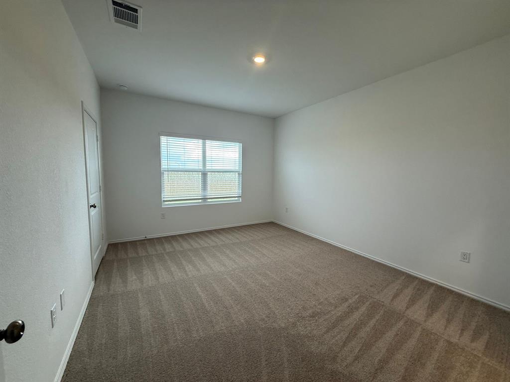 106 Brabham Loop Hutto, TX 78634 - Photo 21 of 40 Neutral-toned carpeting, white walls, and a window with blinds define this room