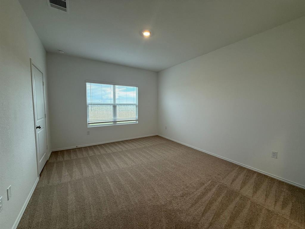 106 Brabham Loop Hutto, TX 78634 - Photo 23 of 40 Carpeted room featuring a window with horizontal blinds, white baseboards, a white door with black hardware, and an overhead recessed light