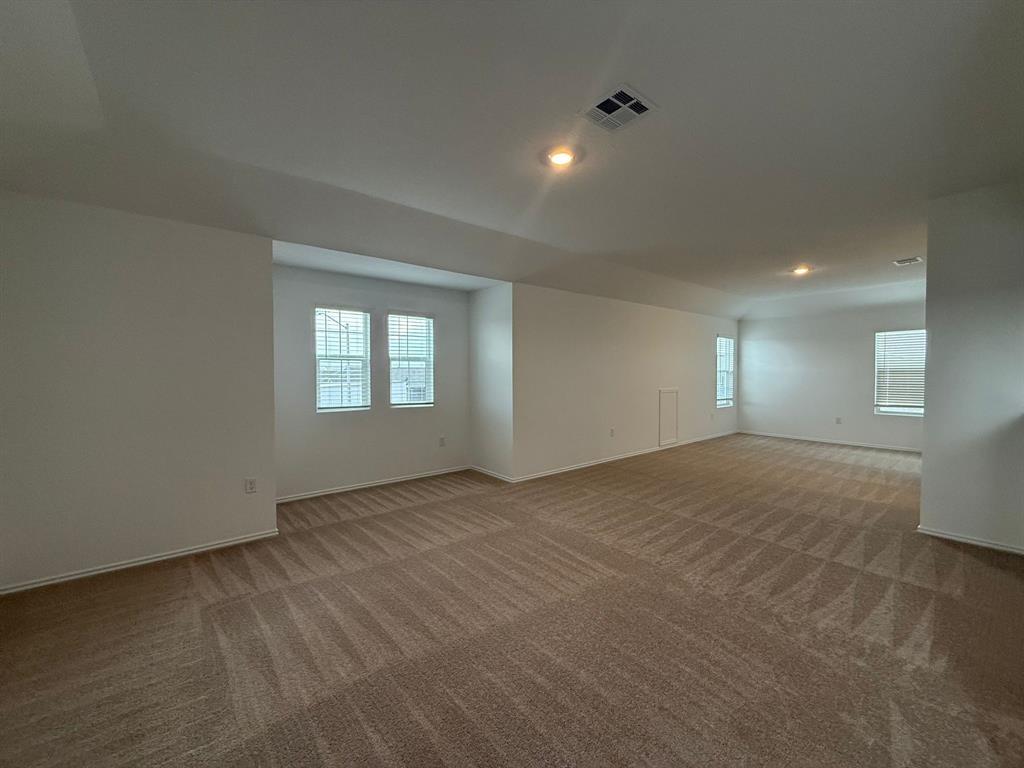 106 Brabham Loop Hutto, TX 78634 - Photo 27 of 40 Spacious room featuring neutral carpeting, multiple windows with blinds, recessed lighting, and crisp white walls