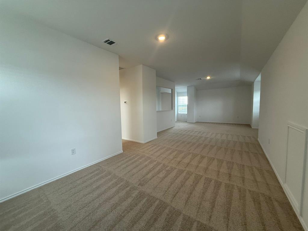 106 Brabham Loop Hutto, TX 78634 - Photo 28 of 40 Spacious interior featuring neutral carpeting, white walls, recessed lighting, and a partial wall opening