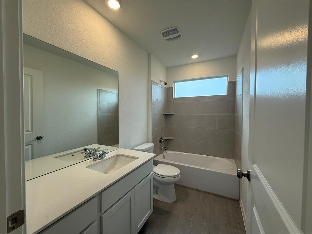 106 Brabham Loop Hutto, TX 78634 - Photo 33 of 40 Bathroom featuring a combined tub/shower with tiled surround, a long horizontal window, and recessed lighting