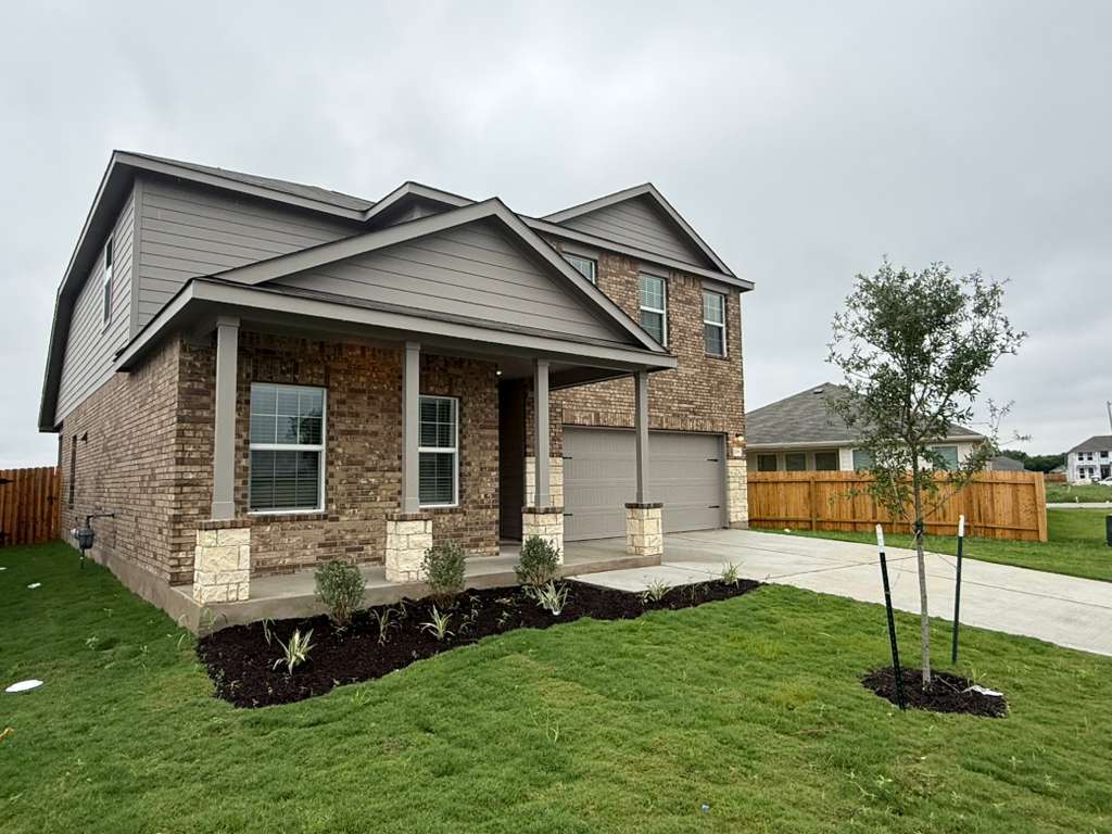 106 Brabham Loop Hutto, TX 78634 - Photo 4 of 40 Two-story residence featuring a brick and siding exterior, a covered front porch with stone-wrapped columns, a two-car garage, and a concrete driveway