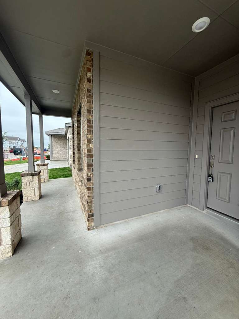 106 Brabham Loop Hutto, TX 78634 - Photo 5 of 40 Covered concrete porch featuring stone-clad pillars, brick veneer accents, horizontal siding, and recessed ceiling lighting