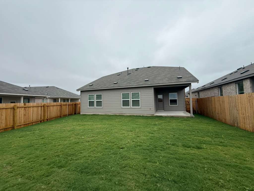 106 Brabham Loop Hutto, TX 78634 - Photo 7 of 40 Expansive backyard with a manicured lawn, full wood privacy fencing, covered patio, and light gray siding exterior