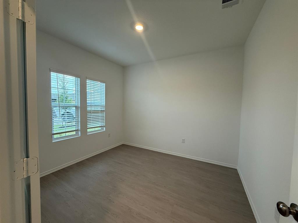 106 Brabham Loop Hutto, TX 78634 - Photo 10 of 40 Room featuring wood-finish flooring, two large windows with horizontal blinds, neutral wall paint, a ceiling-mounted light fixture, and crown molding