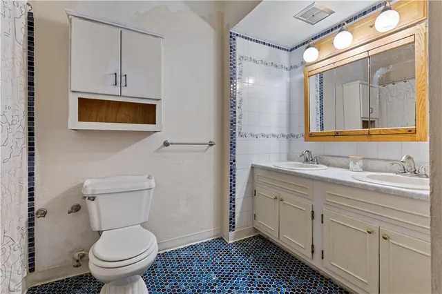 a bathroom with a granite countertop toilet sink and mirror