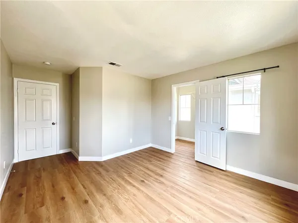 an empty room with wooden floor and windows