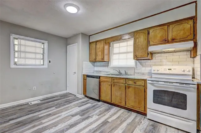 a kitchen with granite countertop wooden cabinets stainless steel appliances a sink and a large window