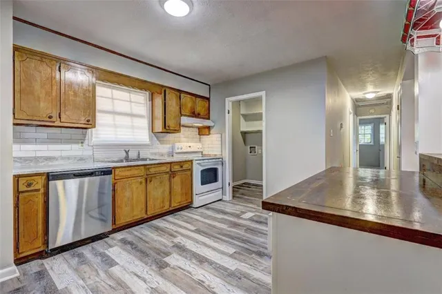 a kitchen with stainless steel appliances granite countertop sink stove refrigerator and cabinets