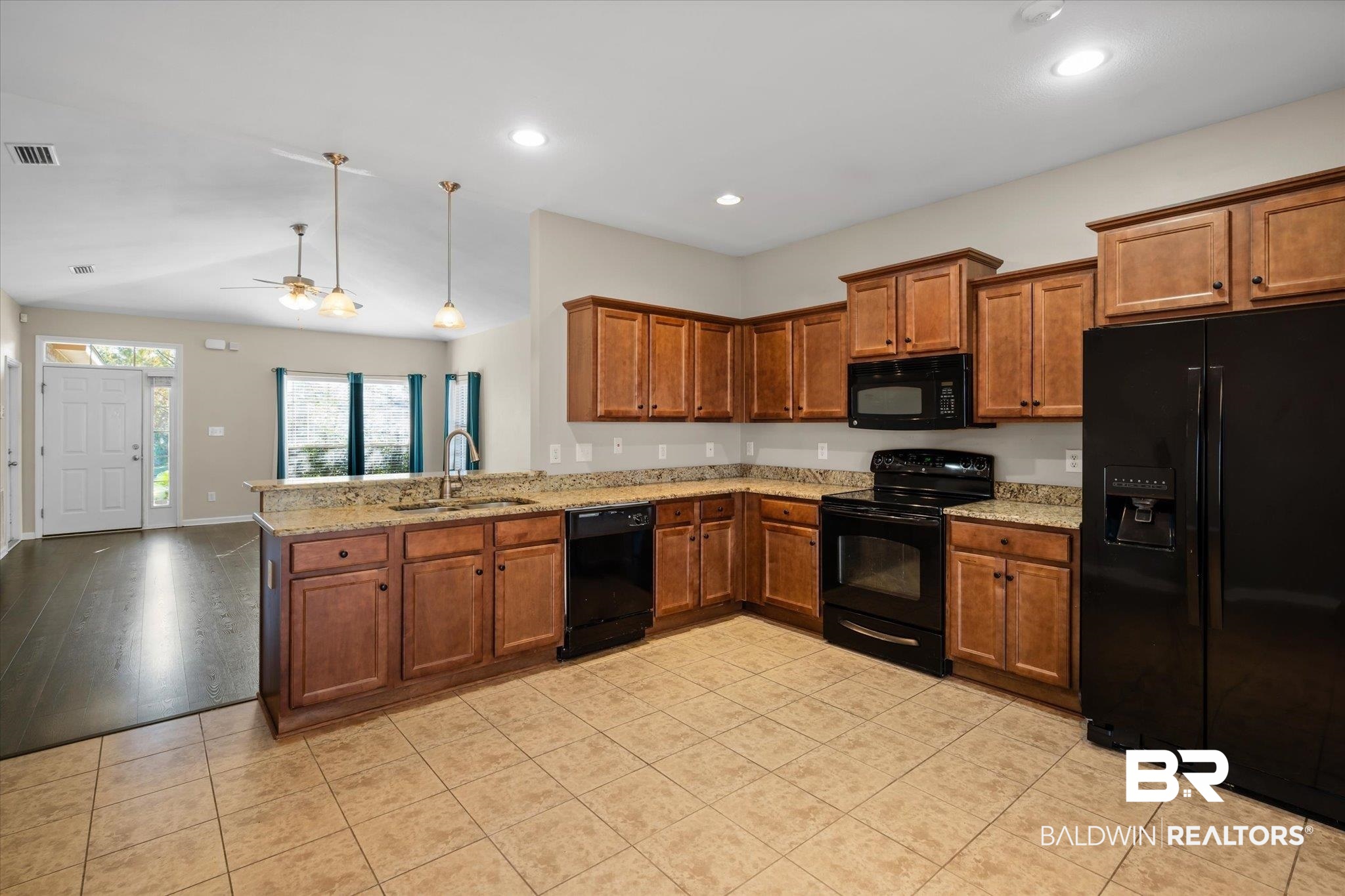 10251 Fionn Loop Daphne, AL 36526 - Photo 6 of 28 Kitchen with black appliances, sink, ceiling fan, light stone counters, and kitchen peninsula