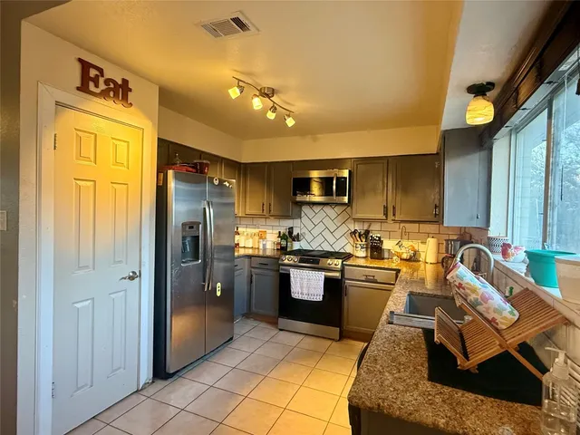 a kitchen with stainless steel appliances granite countertop a refrigerator stove and sink