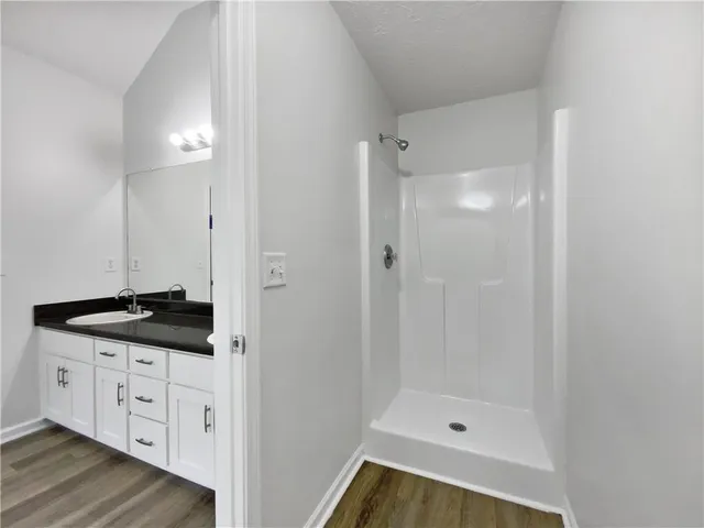 a bathroom with a granite countertop sink a mirror a bathtub and shower