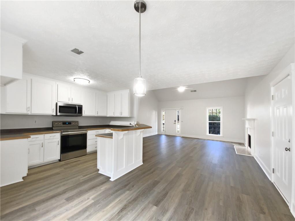 107 Jasons Ridge Griffin, GA 30223 - Photo 2 of 24 a kitchen with stainless steel appliances granite countertop a sink a stove a refrigerator and white cabinets with wooden floor