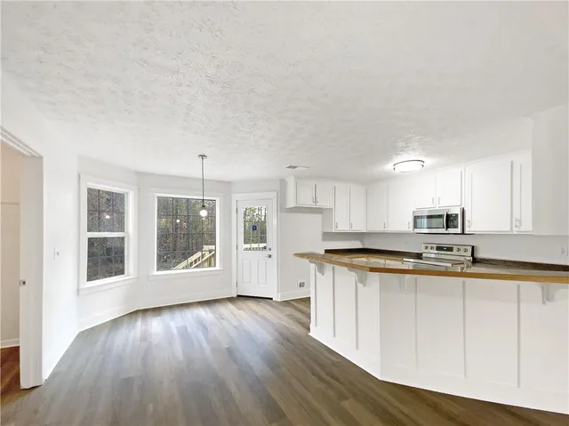 a kitchen with stainless steel appliances granite countertop a stove a sink a refrigerator white cabinets and wooden floor