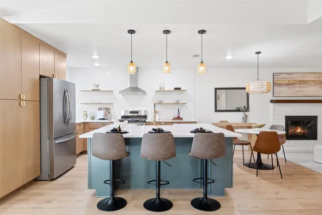 a open kitchen with stainless steel appliances a stove a sink dishwasher and white cabinets with wooden floor