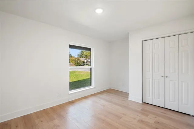 a view of empty room with window and wooden floor
